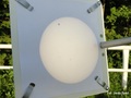 Obraz tarczy słonecznej rzutowanej na ekran. Widoczna jest ciemna okrągła plamka – to Wenus przechodząca przed Słońcem, oraz niewielkie plamy słoneczne. Fot. Jerzy Speil

